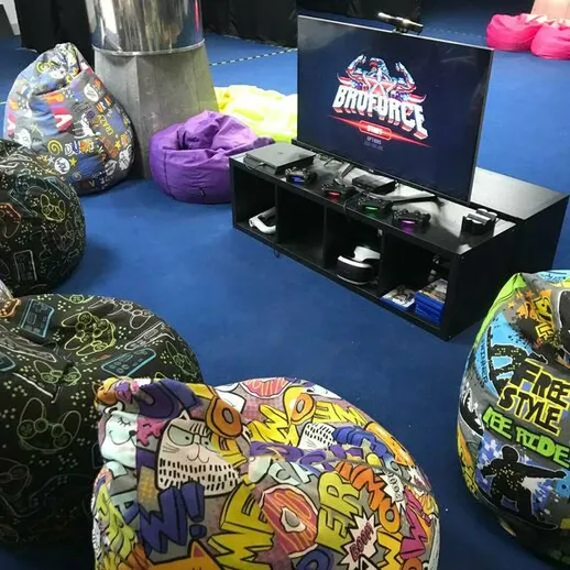 Игровая зона с мягкими пуфами и телевизором, где проходят соревнования по видеоиграм в веселой атмосфере