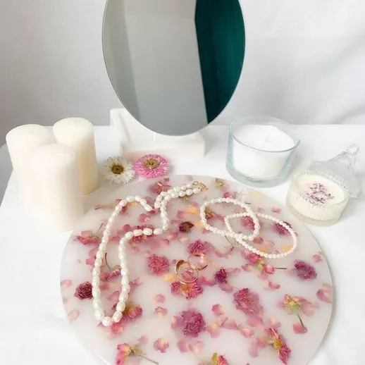 Украшения из жемчуга и сушеные цветы на столе с зеркалом и свечами