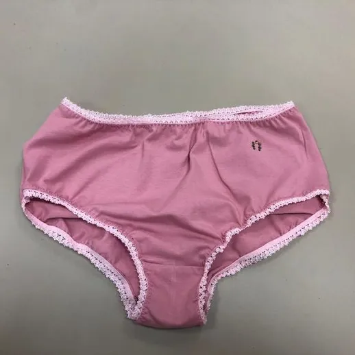 Розовые трусики с кружевом на сером фоне, лежащие на столе