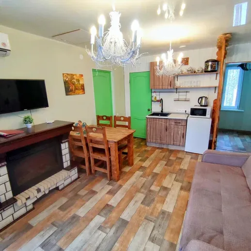 Уютная гостиная с кухней и столовой в светлом интерьере на даче