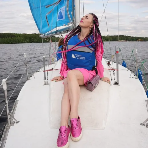 Парусная регата на озере с участником в ярком наряде, наслаждающимся ветерком, летом в расслабленной атмосфере