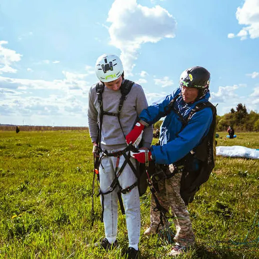 Подготовка к парапланеризму на живописном поле под голубым небом в солнечный день