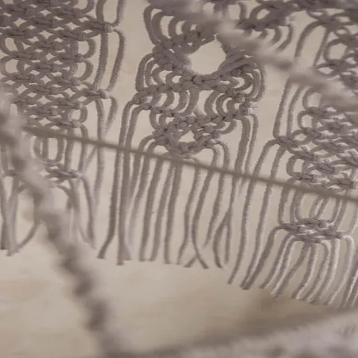 Искусно выполненное макраме с петельками на фоне светлой стены в мастерской, создаваемое в утренние часы