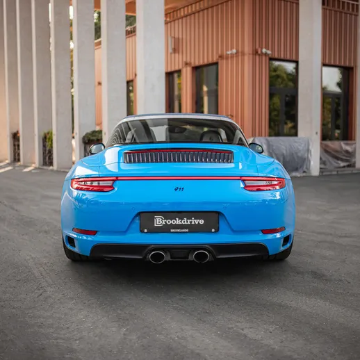 Синий автомобиль стоит на парковке рядом с зданием в ясный день