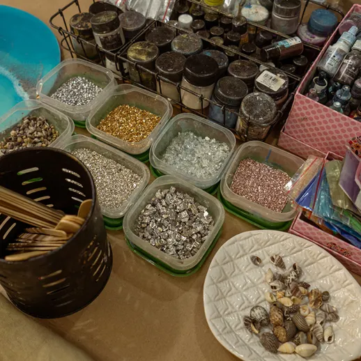 Разнообразные материалы для творчества на рабочем столе в мастерской, включая блестки, ракушки и краски