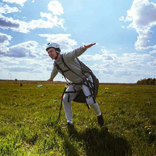 Прыжок в небе с парапланом на фоне яркого неба и облаков в солнечный день на открытом поле