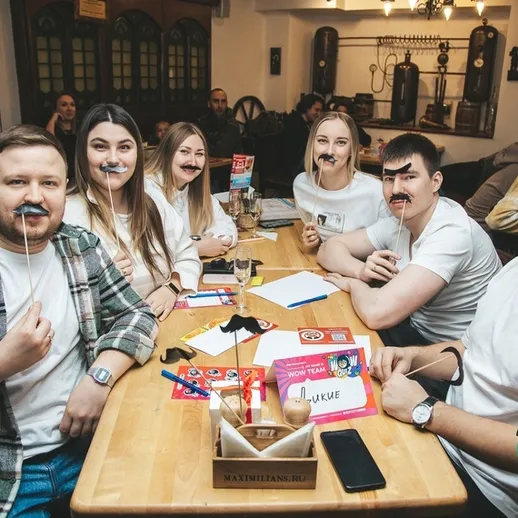 Смех и веселье на вечеринке в кафе с участниками викторины и играми в масках усов