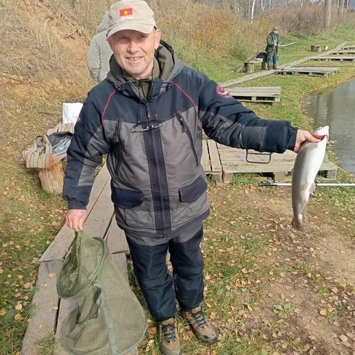 Рыбак на берегу пруда с уловом у насаженной рыбы в осенний день