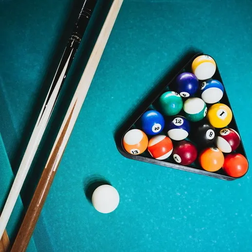 Игровой момент с бильярдными шарами на синем столе, подготовка к партии в бильярд, вечерняя игра
