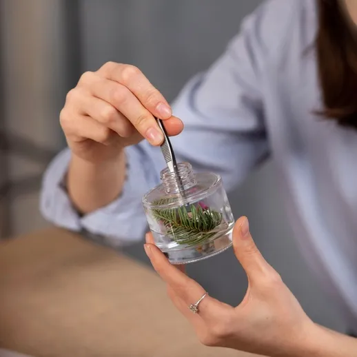 Женщина держит контейнер с растениями и анализирует их в помещении