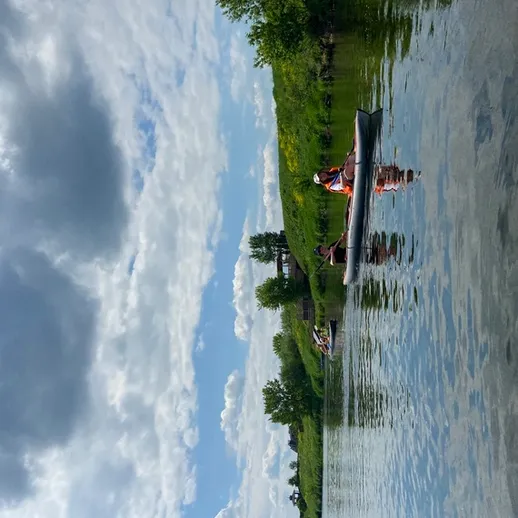 Люди каякают на спокойной воде в живописном месте под облачным небом в летний день