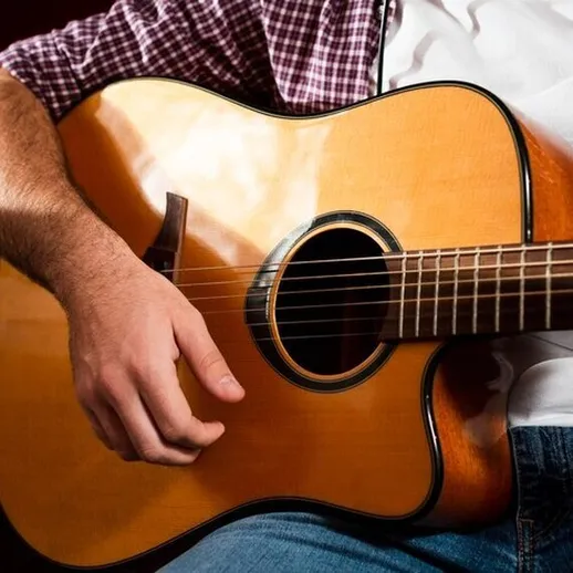 Игрок на гитаре сидит в уютной обстановке и наслаждается процессом игры