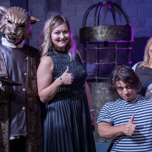 Четыре человека на мероприятии в тематическом костюме, в зале с фоновым освещением и сценической обстановкой