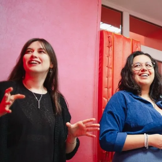 Две женщины говорят и смеются в комнате с розовыми стенами во время вечеринки или встречи