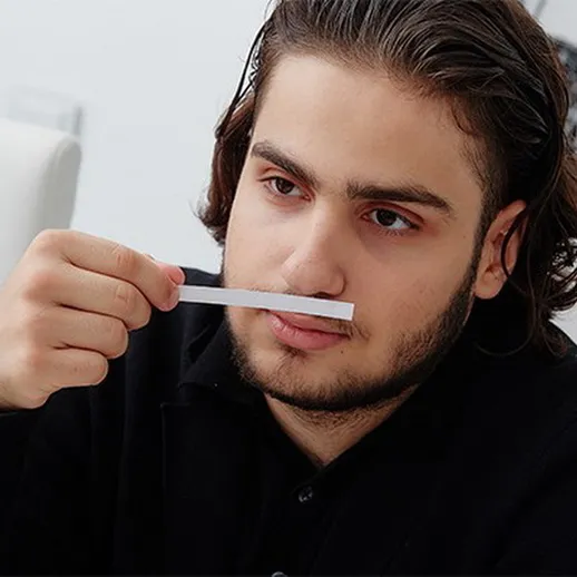 Молодой человек проводит тестирование аромата в комнате для обсуждений, сидя за столом с другими участниками