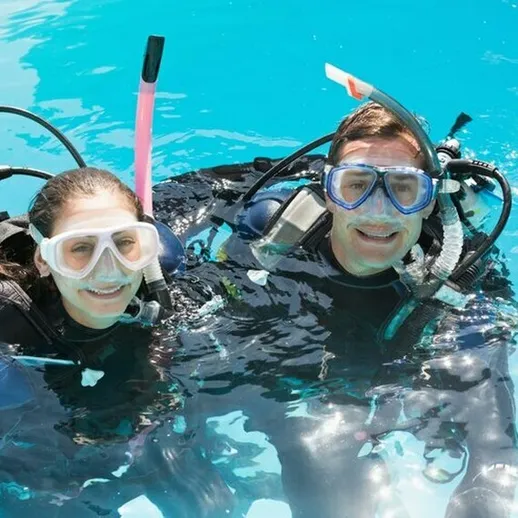 Пары подводного плавания в бассейне с теплой водой в солнечный день