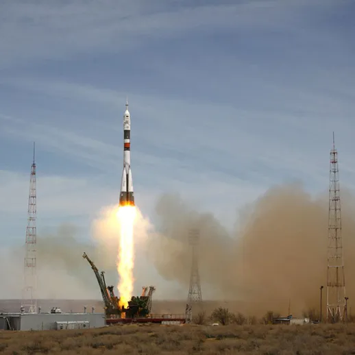 Запуск ракеты с космодрома в Казахстане в ясный день, сопровождаемый большим облаком дыма