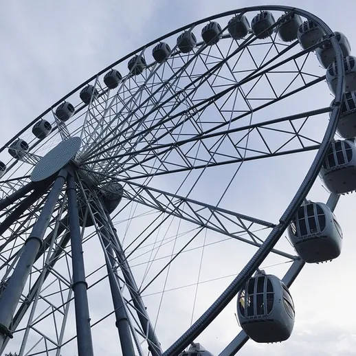 Колесо обозрения на фоне неба с облаками в день отдыха