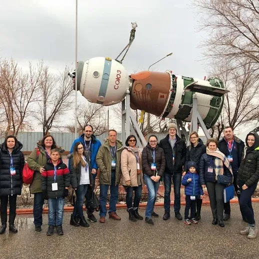 Экскурсия на космодром: группа людей позирует у космического аппарата в зимний день