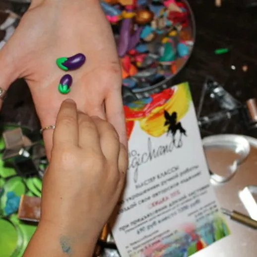 Рука с разноцветной краской на фоне художественных принадлежностей в творческой мастерской