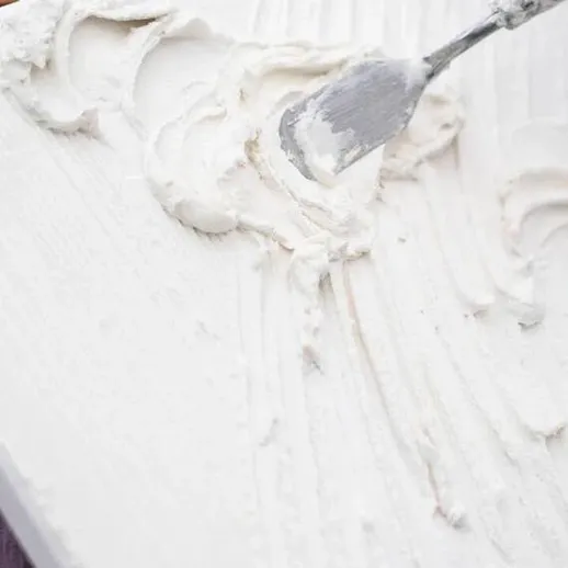 Наносите крем на торт в кухне с натуральной подсветкой во время создания десерта