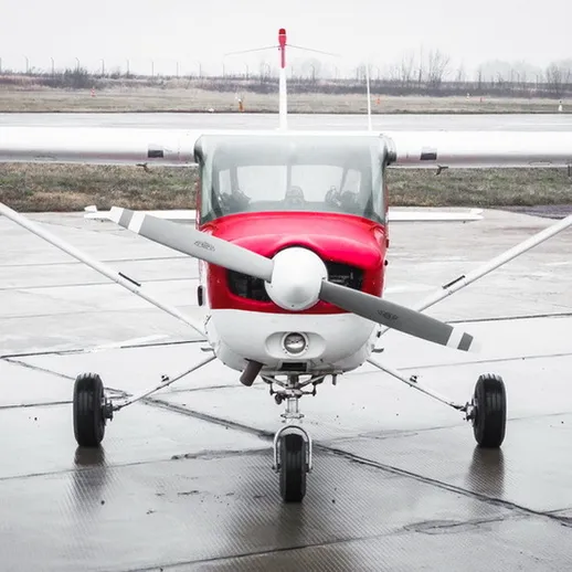 Красный легкий самолет на аэродроме в дождливую погоду с неровной местностью и низким слоем облаков