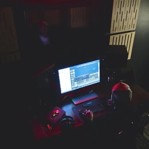 Музыкальная студия в ночь: звукорежиссер за работой с компьютером в непринужденной обстановке