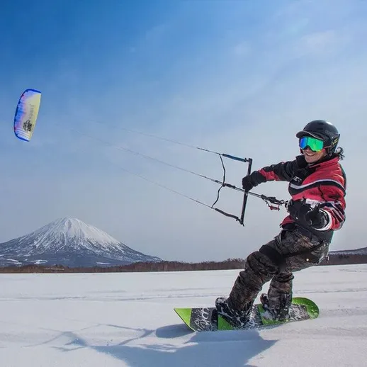 Кайтсёрфинг на заснеженной равнине у горы в ясный день