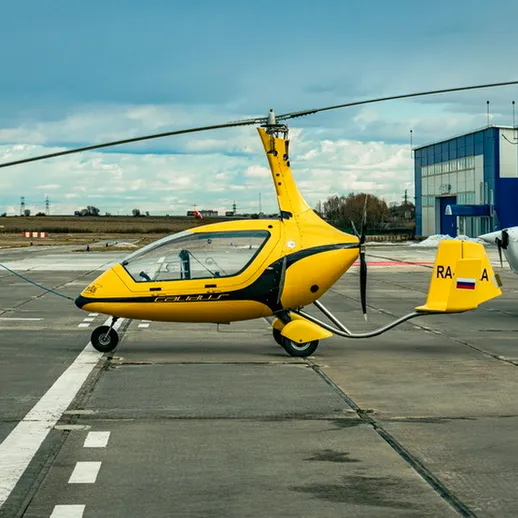 Жёлтый вертолёт стоит на взлётной полосе аэропорта в ясный день