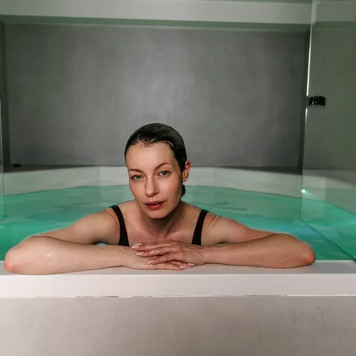 Женщина расслабляется в ванной с водой в современном интерьере