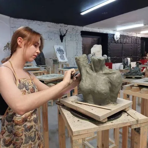 Женщина создаёт скульптуру из глины в художественной студии в вечернее время