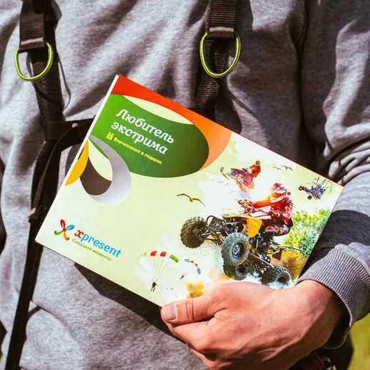 Человек на природе держит в руках коробку с подарком для любителей экстрима,  солнечный день за городом