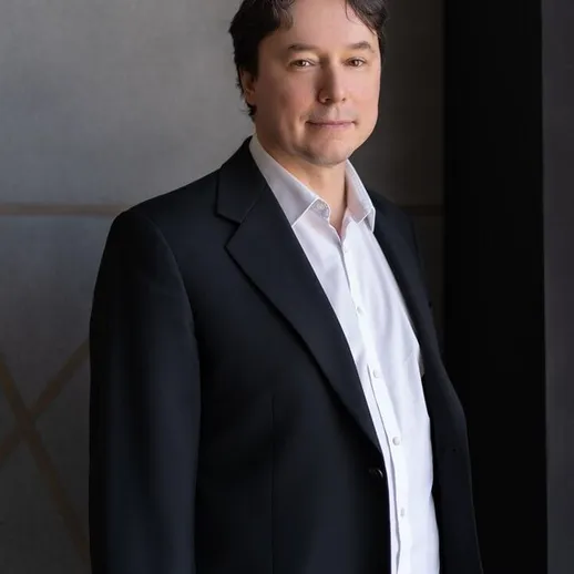 Мужчина в строгом костюме стоит у окна в современном помещении