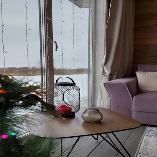 Уютный зимний вечер в загородном доме с елкой, диваном и видом на снежный пейзаж