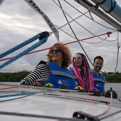 Трое людей на яхте наслаждаются ветром и важным моментом в плавании у берега реки на закате