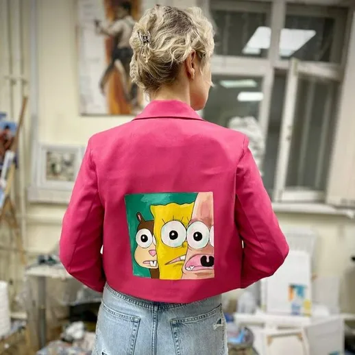 Ярко-розовый пиджак с мультяшным рисунком на спине в мастерской художника