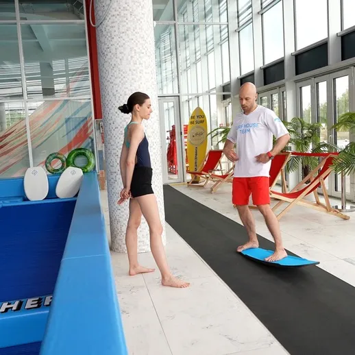 Тренировка на балансировочной доске в спортзале у бассейна с инструктором и учеником