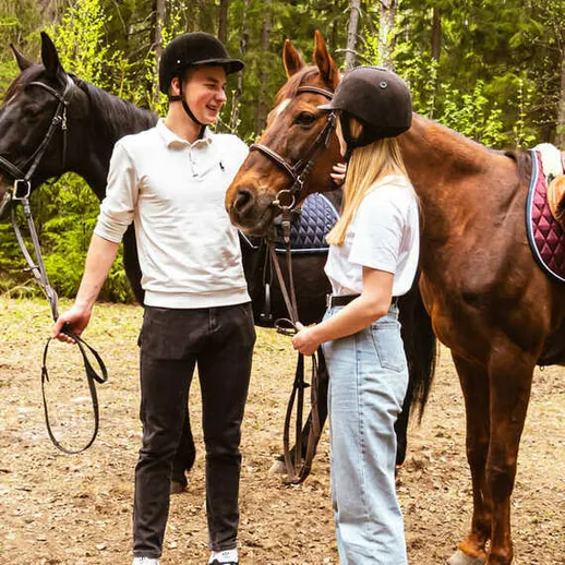 Молодая пара общается с лошадьми в лесу, наслаждаясь природой во время верховой езды Молодая пара общается с лошадьми в лесу, наслаждаясь природой во время верховой езды