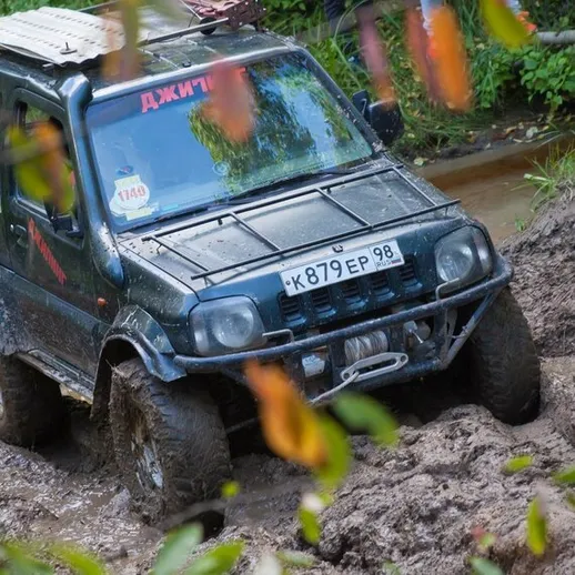 Джип преодолевает грязевой участок в лесу во время приключенческого off-road тура