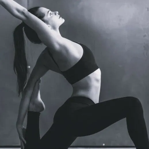 Энергичная женщина выполняет йогу в студии в естественном освещении, демонстрируя гибкость и концентрацию