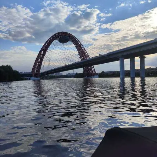 Мост через реку, вид с воды, яркое небо и облака в день