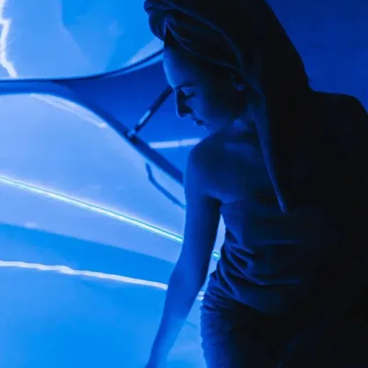 Молодая женщина с полотенцем у голубого светящегося стекла в уединенном пространстве