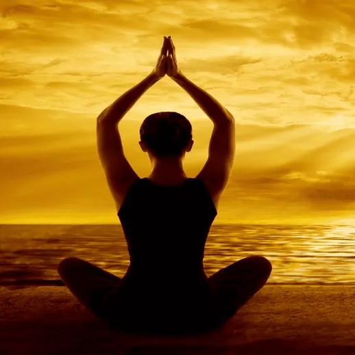 Женщина занимается йогой на берегу океана во время заката