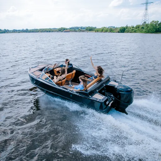 Молодые люди наслаждаются катанием на моторной лодке по озеру в солнечный день