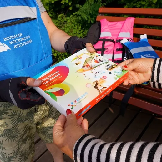 Раздача информационных материалов на набережной в Москве, летнее утро, человек в спасательном жилете