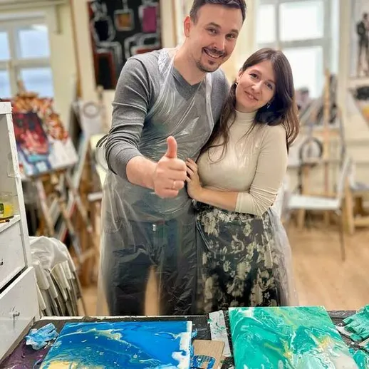 Молодая пара позирует на художественном мастер-классе в уютной студии на фоне своих картин