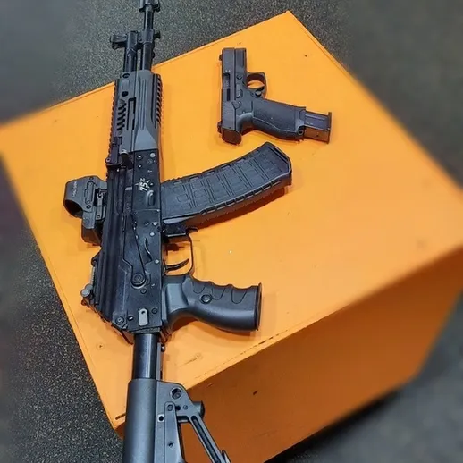 Два современных огнестрельных оружия на ярко-оранжевом козле в помещении