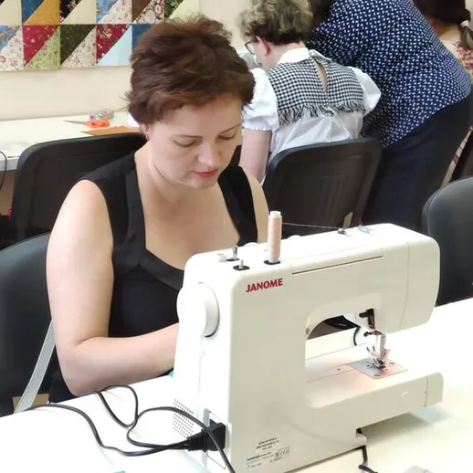 Участница мастер-класса по шитью работает за швейной машинкой в творческой студии