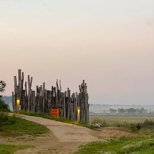 Уединённая тропа к деревянной постройке на фоне утреннего горизонта в тихом ландшафте