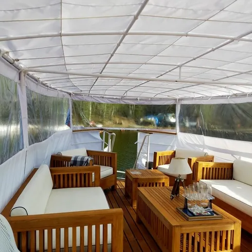 Уютный интерьер лоджии на реке с деревянной мебелью и зоной для отдыха в солнечный день